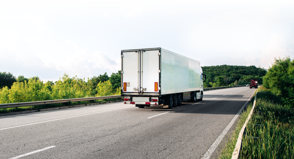 White logistics truck transporting cargo on a highway under a cloudy sky